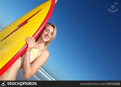 Beautiful blond woman standing with surfboard