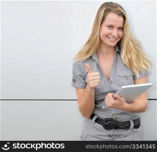 Beautiful blond woman using touchpad on grey background