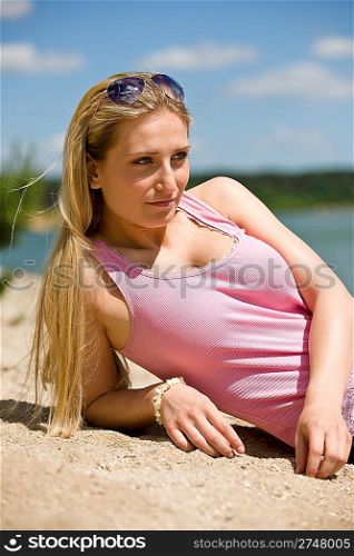 Beautiful blond woman with sunglasses lying on sunny beach