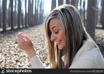 Beautiful blonde girl, dressed with a beige dress, standing in a poplar forest