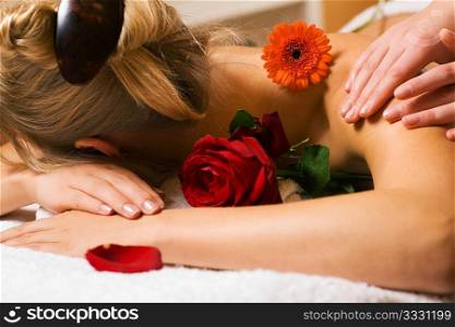 Beautiful blonde girl getting a massage in a spa setting and feeling visibly good about it