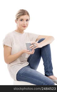 Beautiful blonde girl sitting and drinking coffee, over a white background