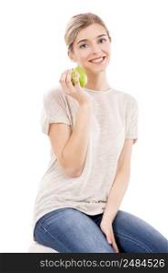 Beautiful blonde girl sitting and holding a green apple, over a white background