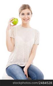 Beautiful blonde girl sitting and holding a green apple, over a white background