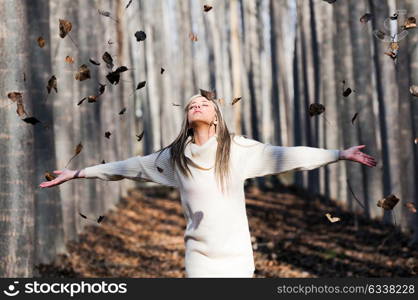 Beautiful blonde girl with falling leaves in the autumn park