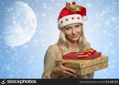 beautiful blonde girl with funny santa claus hat taking christmas gift boxes in the hands and wearing golden winter dress