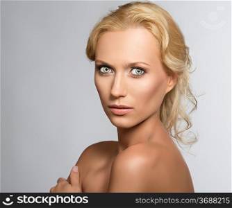 beautiful blonde girl with nudes shoulders and natural makeup, she is turned of three quarters at right, looks in to the lens and her left hand is on the right shoulder