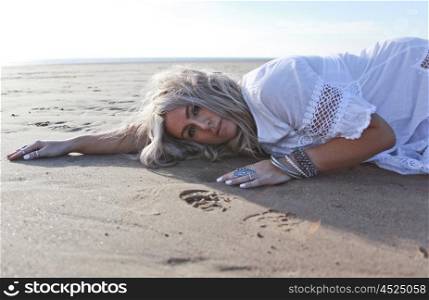 Beautiful blonde haired woman dressed in boho style at the beach