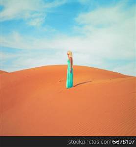 Beautiful blonde in a blue dress in an orange desert. UAE