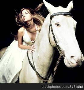 Beautiful blonde in a white dress on a white horse