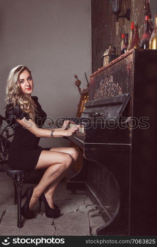 Beautiful blonde in black dress near piano