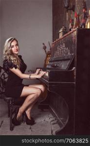 Beautiful blonde in black dress near piano