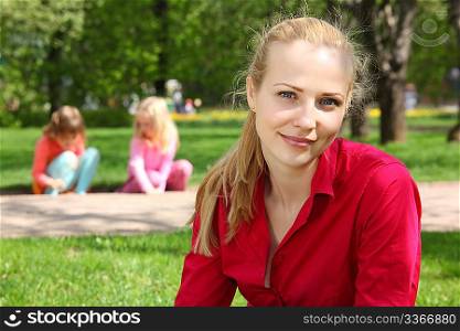 beautiful blonde in park with playing children on background