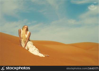 Beautiful blonde in white dress in orange desert. UAE