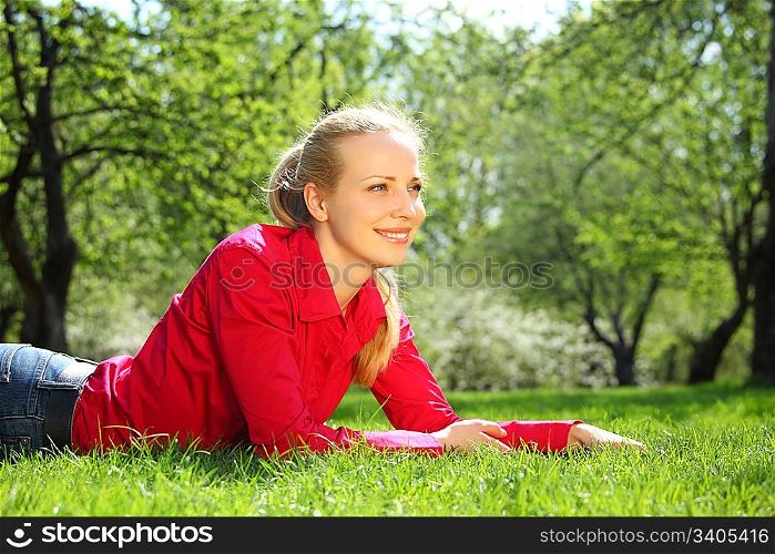 beautiful blonde lies on grass in garden in spring