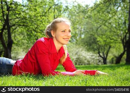beautiful blonde lies on grass in garden in spring