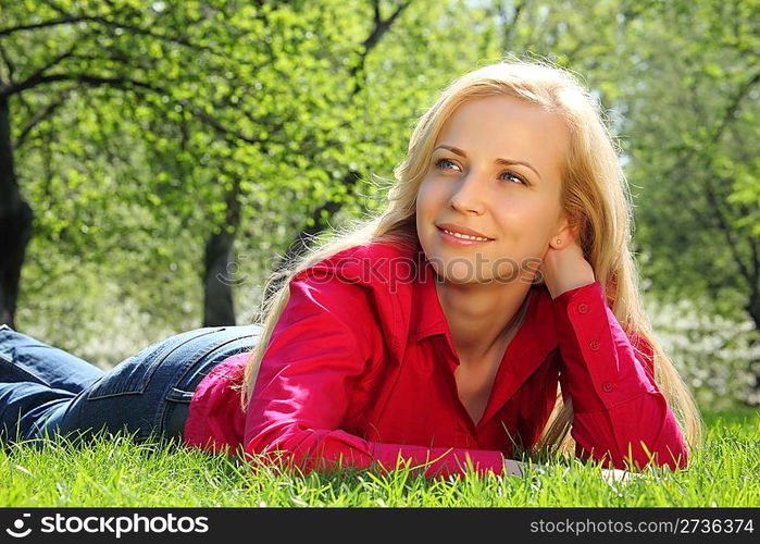 beautiful blonde lies on grass in park in spring