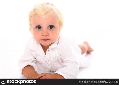 Beautiful blonde little girl lying on the floor and looking directly into the camera on white background close-up