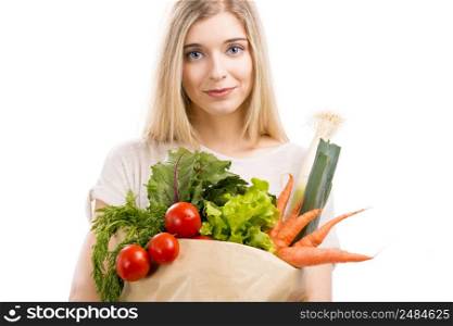Beautiful blonde woman carrying a bag full of vegetables, isolated over white background
