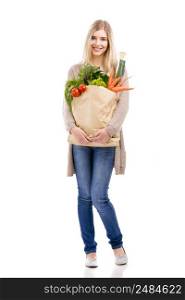 Beautiful blonde woman carrying a bag full of vegetables with thumbs up, isolated over white background