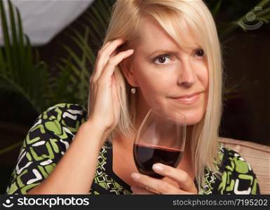 Beautiful Blonde Woman Smiling at an Evening Social Gathering Tasting Wine.