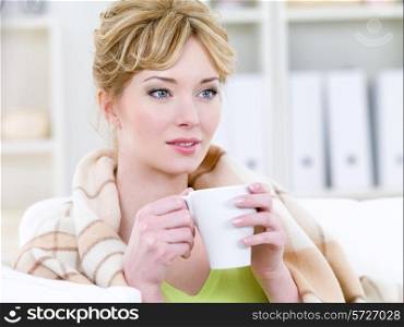Beautiful blonde woman with easy smile drinking warming coffee - indoors