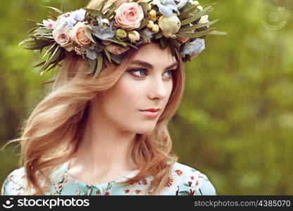 Beautiful blonde woman with flower wreath on her head. Beauty girl with flowers hairstyle. Girl in a summer forest. Fashion photo