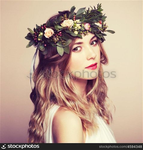 Beautiful blonde woman with flower wreath on her head. Beauty girl with flowers hairstyle. Perfect makeup. Beauty fashion. Spring woman