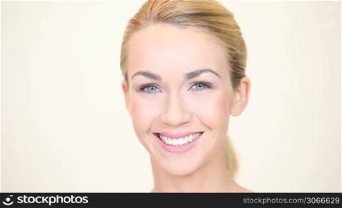 Beautiful blonde woman with her hair tied up in a ponytail facing forwards towards the camera smiling