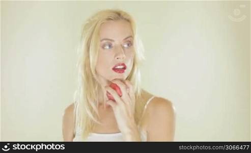 Beautiful blonde woman with long hair and red lipstick playing with a cricket ball against a white studio background