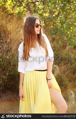 Beautiful blonde young woman in skirt and sunglasses. Female model wearing fashionable clothes and walking on the street