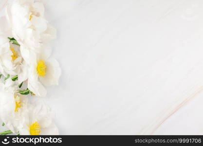 Beautiful blooming white peony flowers on marble background with copy space in minimal style, template for postcard, lettering, text or your design. Wedding invitation and celebration greeting concept