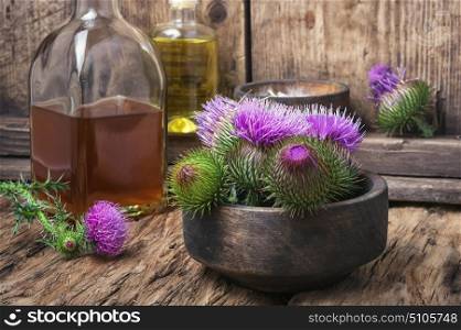Beautiful blossoming buds thistle. Wild plant thistle also medicinal tincture on a wooden surface
