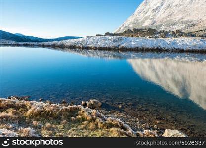 Beautiful blue lake in the mountains, morning sunrise time. Landscape with snow and frozed nature
