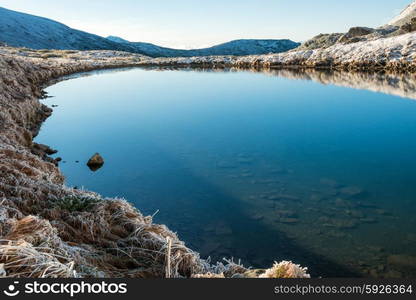 Beautiful blue lake in the mountains, morning sunrise time. Landscape with snow and frozed nature