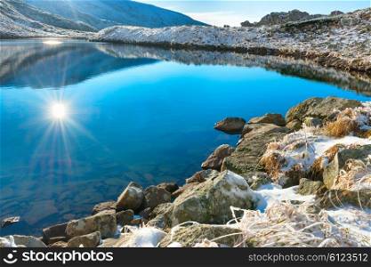 Beautiful blue lake in the mountains, sunset time. Landscape with sun and reflection in water