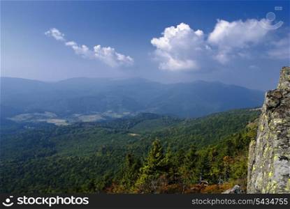 Beautiful blue sky and forest high up in Carpathian mountains. Top view from rock