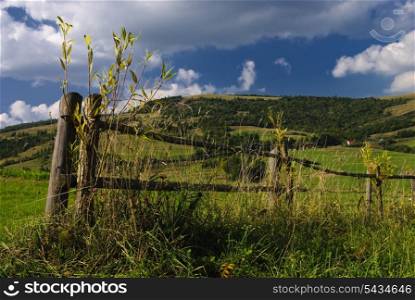 Beautiful blue sky and green grass and meadows with fence in Carpathian mountains