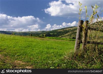 Beautiful blue sky and green grass and neadows with fence in Carpathian mountains