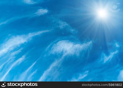 Beautiful blue sky, fluffy white clouds and shining sun with rays