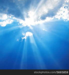 Beautiful blue sky with sunbeams and clouds. Sun rays.