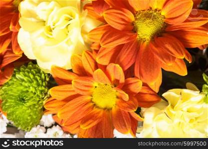 Beautiful bouquet of bright flowers in white basket on white tablecloth. Flowers in a basket