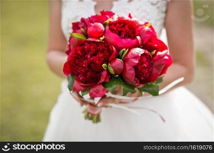Beautiful bouquet of bright red peonies in the hands of a girl.. A bouque of red peonies in the hands of a bride in a wedding dress 2824.