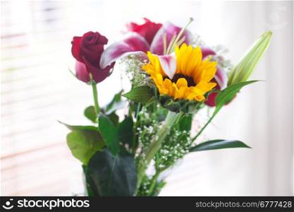beautiful bouquet of sunflowers, lily and roses in a vase