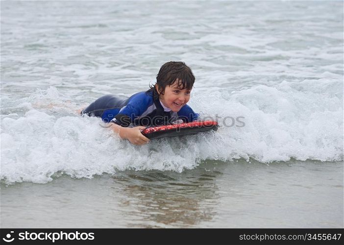 Beautiful boy sliding on the waves with surfboard