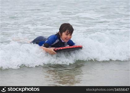 Beautiful boy sliding on the waves with surfboard