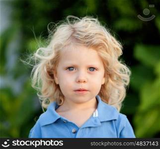Beautiful boy three year old with long blond hair in the park