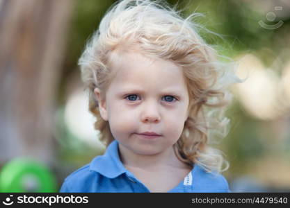 Beautiful boy three year old with long blond hair on a sunny day