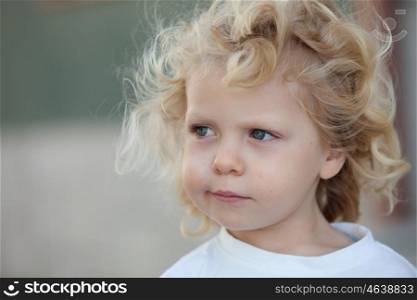 Beautiful boy three year old with long blond hair on a sunny day