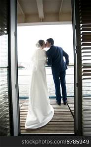 Beautiful bride and groom kissing on balcony of hotel room